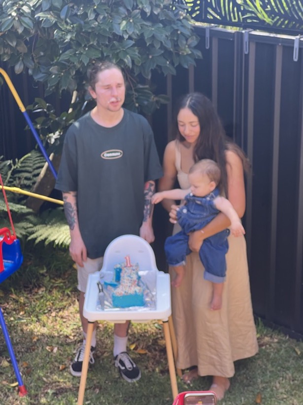 Brittany and Deklan gathered outside with a child and birthday cake.
