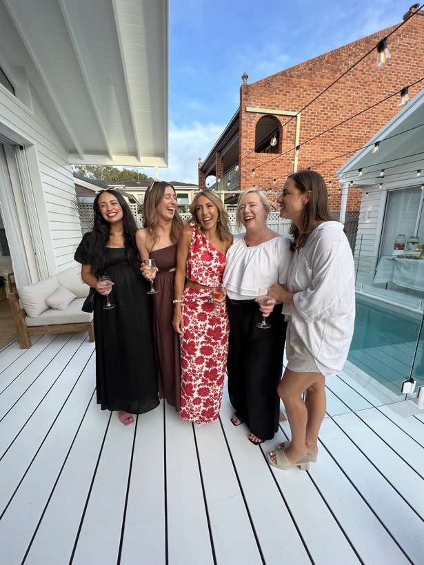A group of women laughing together near a pool.