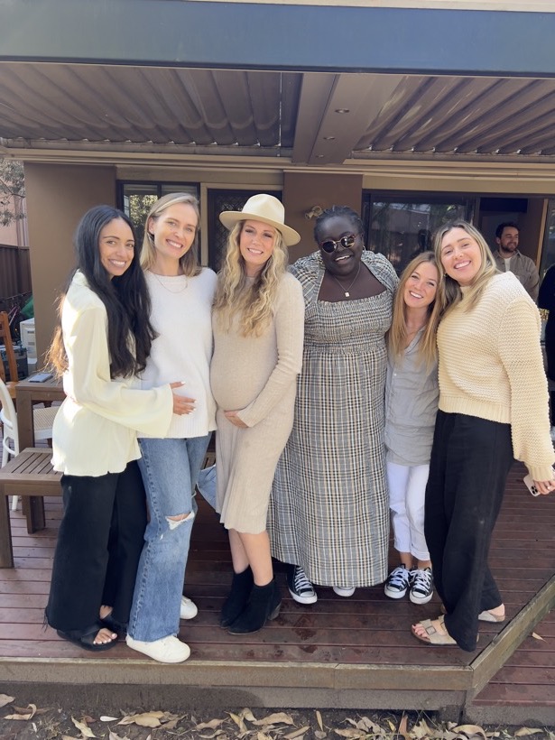 A group of women gathered closely together and smiling.